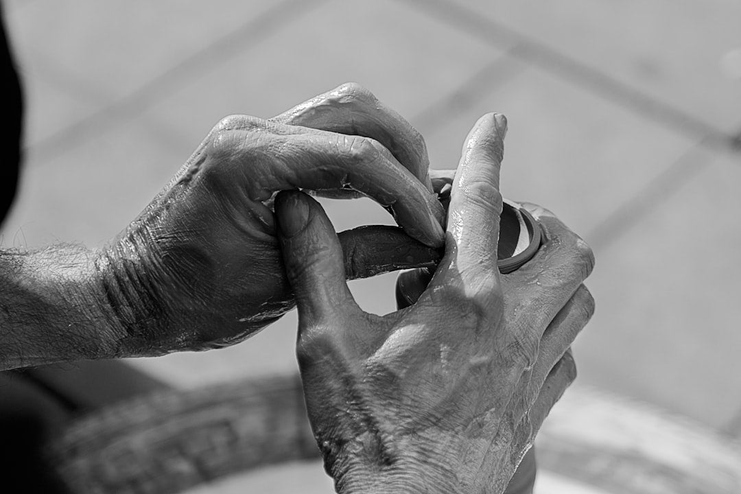 Close-up black and white photo of elderly hands carefully opening a small container, symbolizing aging, care, and daily living challenges.